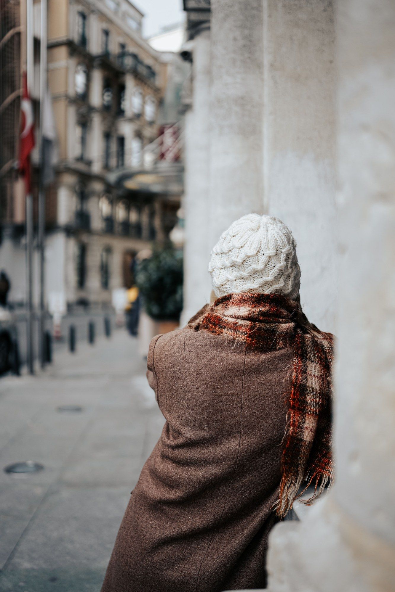 Mujer con abrigo y gorro caminando por una calle urbana en invierno