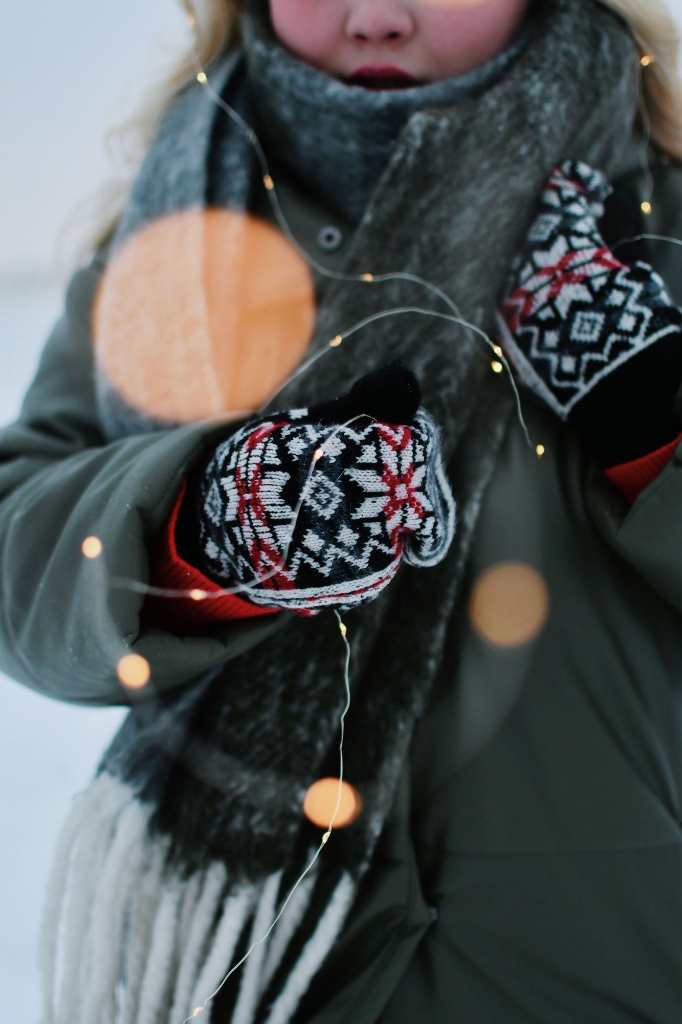 Guantes tejidos, bufanda y luces cálidas en una escena de invierno